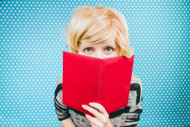Mujer joven cubriÃ©ndose con un libro rojo